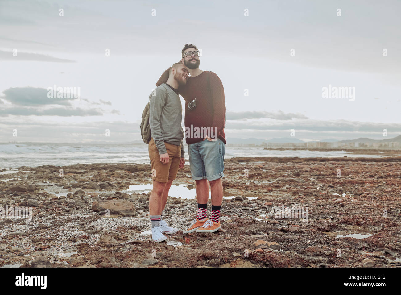 Happy young gay couple standing on the beach Stock Photo