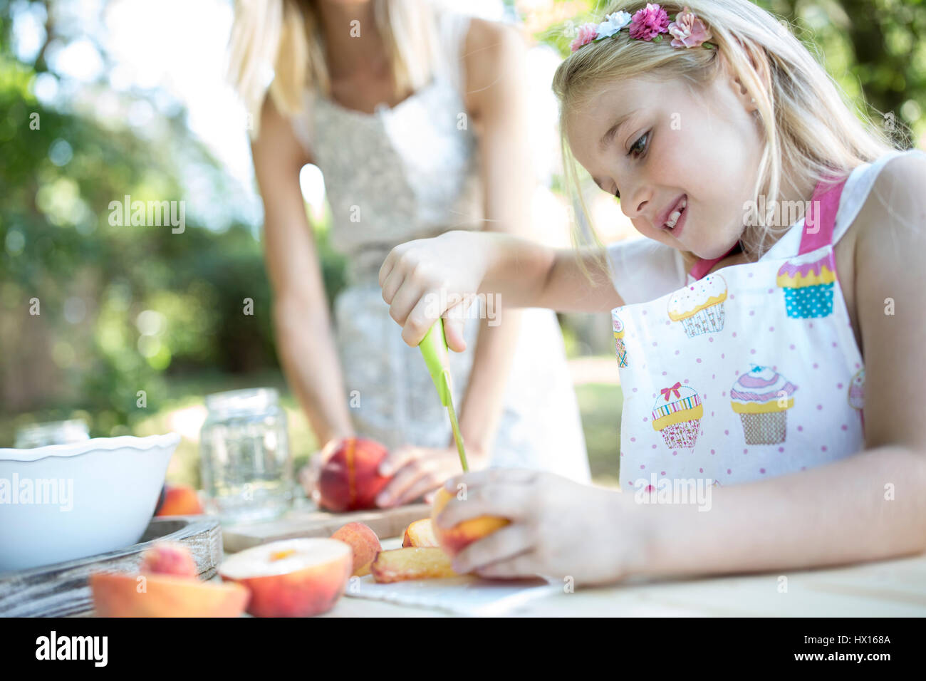 Girl preserving peaches at garden table Stock Photo