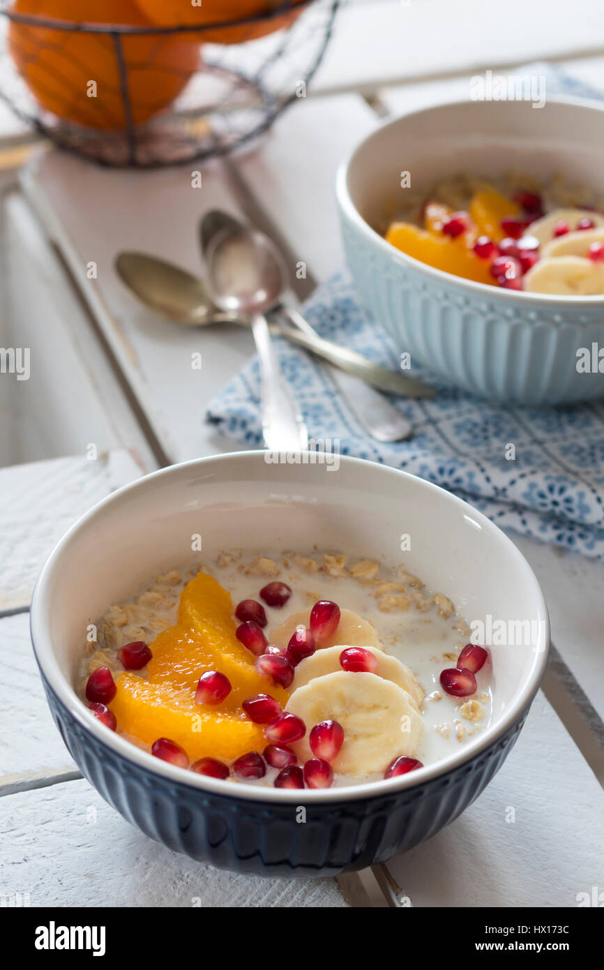 Soaked oat flakes in milk with banana, orange and pomegranate seeds Stock Photo