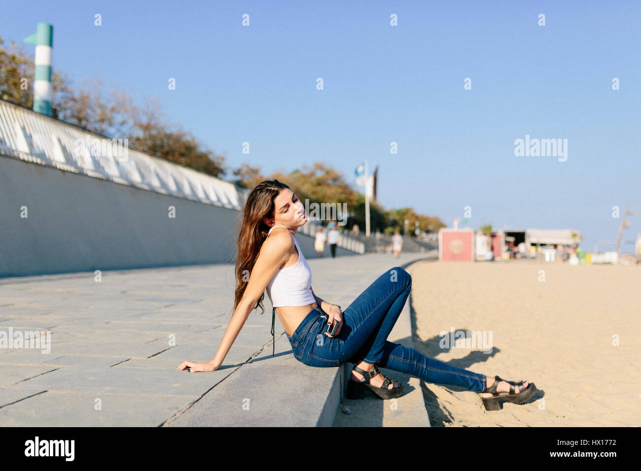 Young woman relaxing on beach promenade at sunset Stock Photo - Alamy