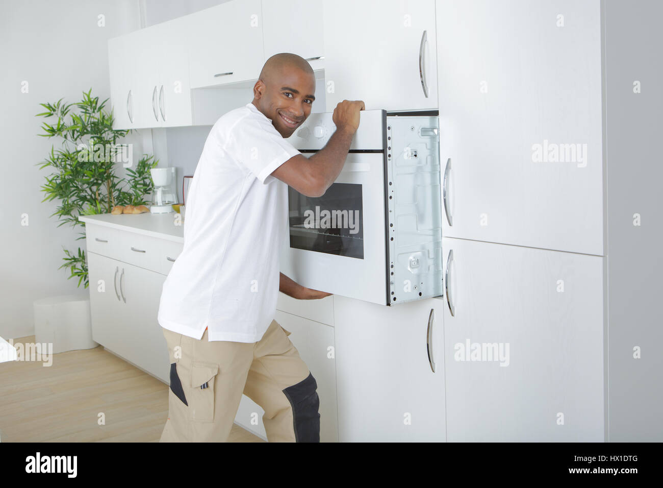worker installing modern built-in oven in kitchen Stock Photo