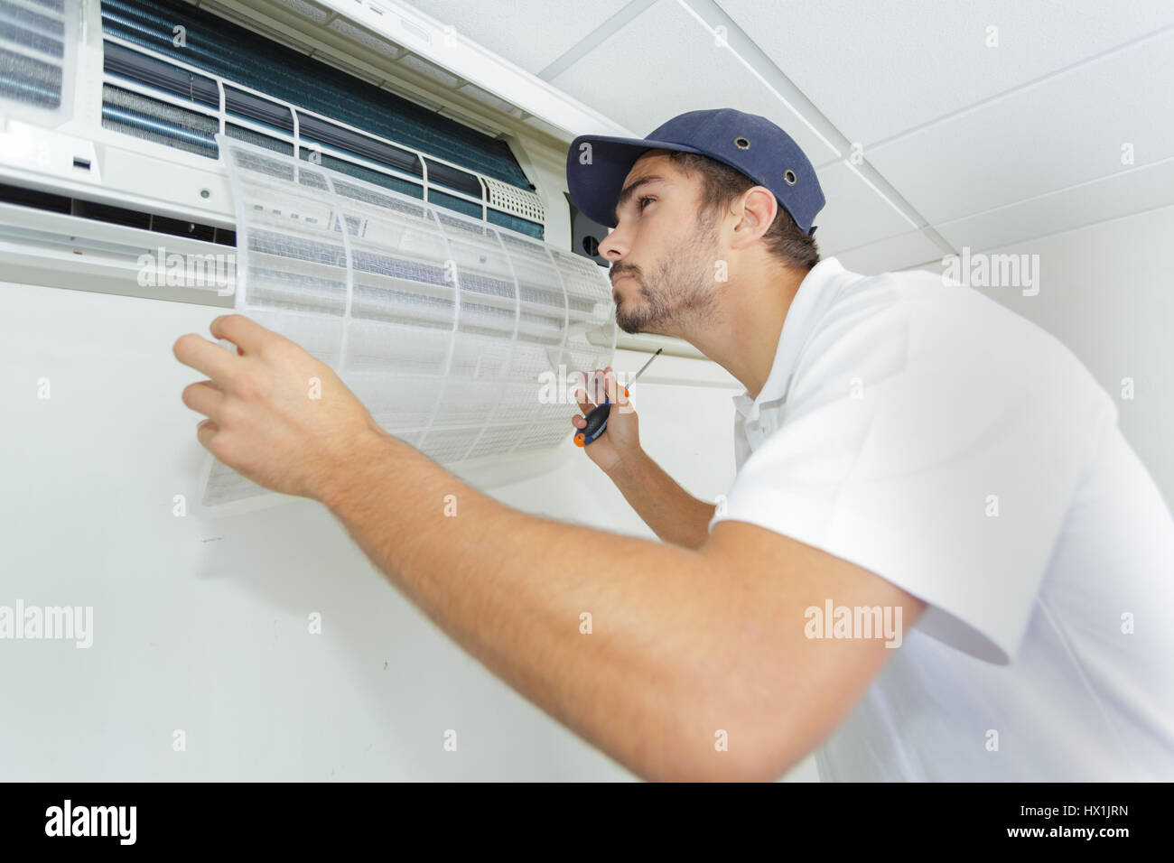 portrait of midadult male technician repairing air conditioner Stock