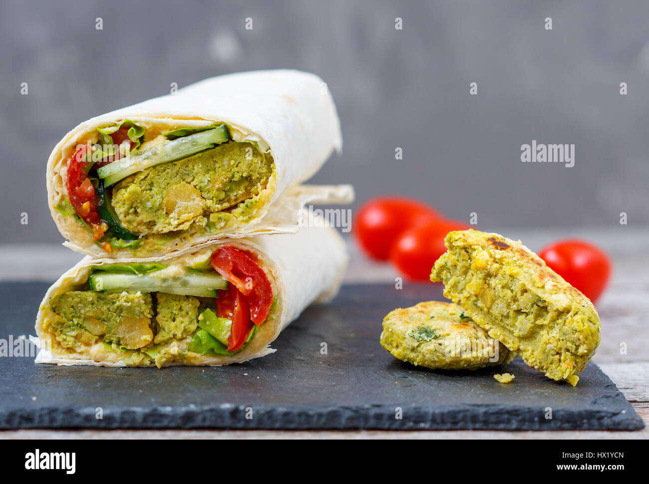 Green falafel with hummus and vegetables in pita bread on a slate and dark background. Love for a healthy vegan food concept Stock Photo