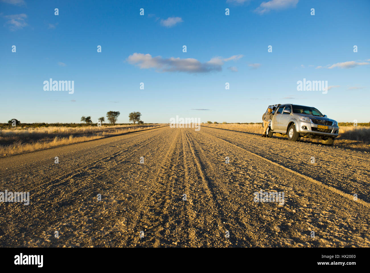 Woman stands at an offroad vehicle on gravel road C 17 near Keetmanshoop, Namibia Stock Photo