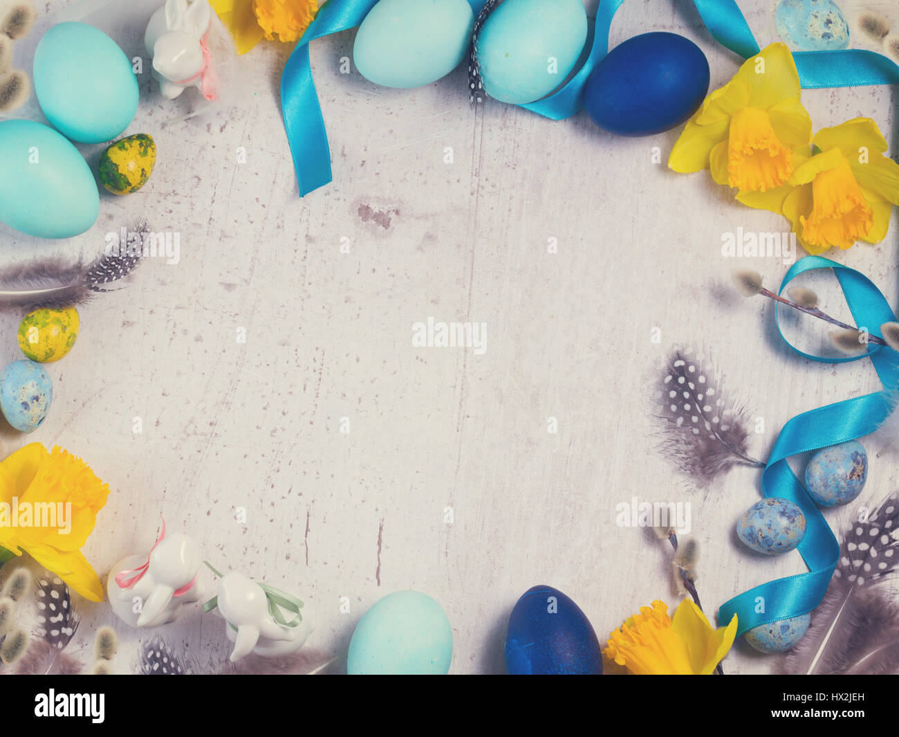 Easter frame with painted blue eggs and flowers on aged wooden desktop ...