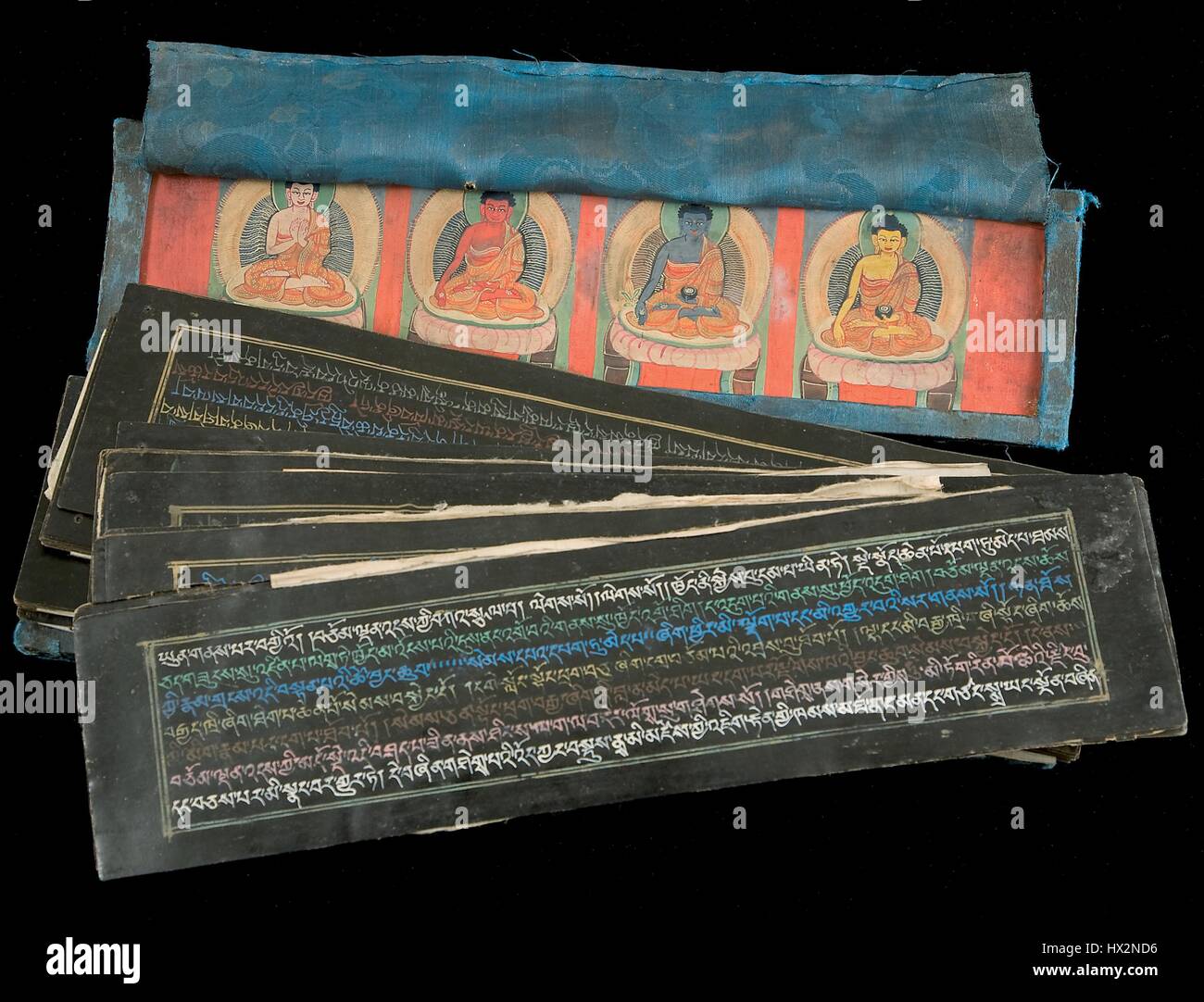 Leaves and the upper book cover of Tharpa chenpo'i Do (Sutra of Great Liberation), showing Tibetan writings on black paper and the upper book cover showing images of four of the Eight Medicine Buddhas, 3879. Courtesy National Library of Medicine. Stock Photo