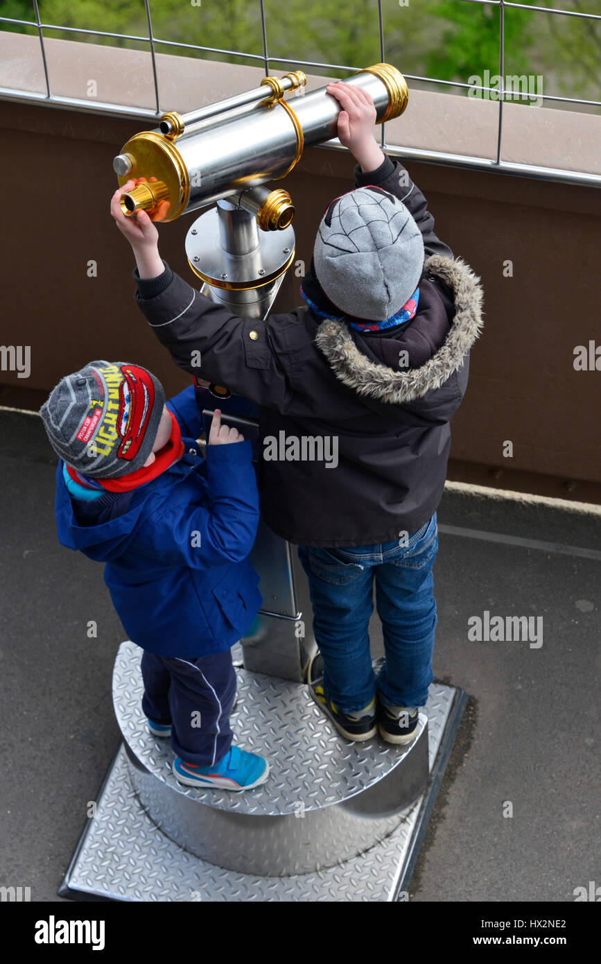 Two small kids trying to view through a telescope larger than themselves. Here at the Eiffel Tower in Paris. Stock Photo