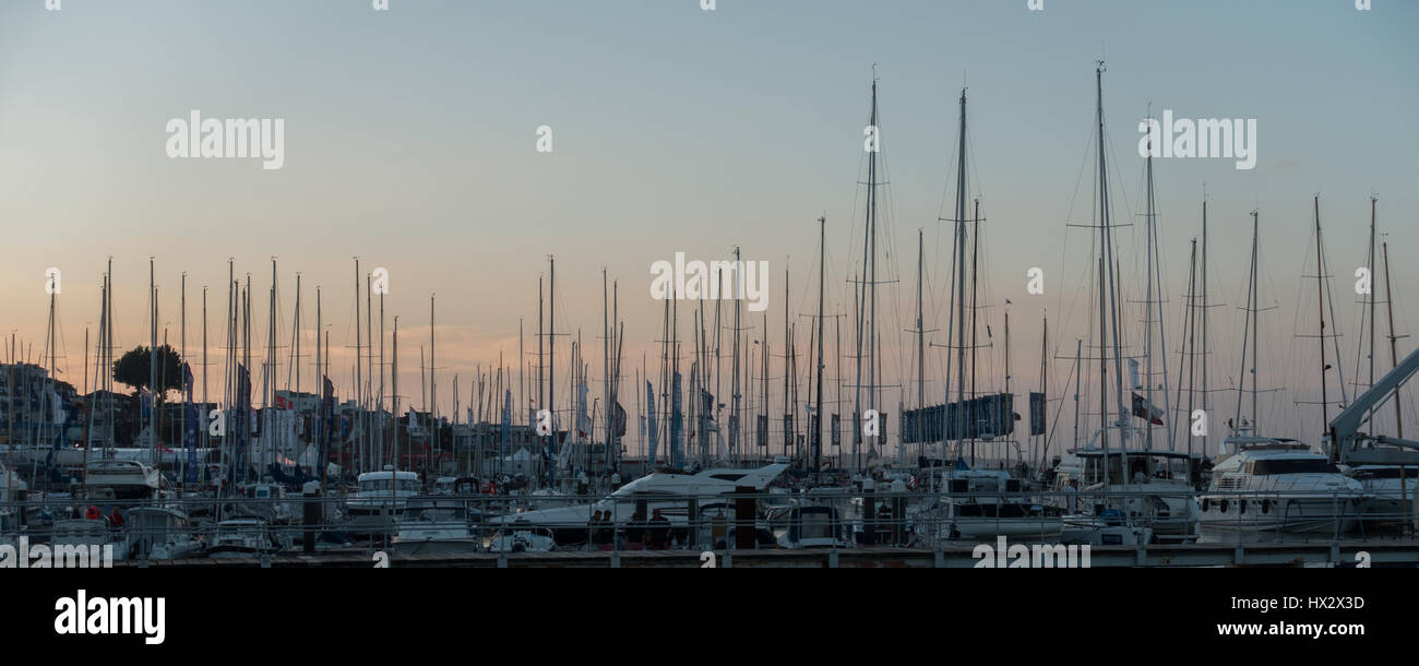 many masts silhouette against a sunset over Cowes Harbour Marina on a quiet still dusk summer August twilight Cowes Week regatta, Cowes UK Stock Photo