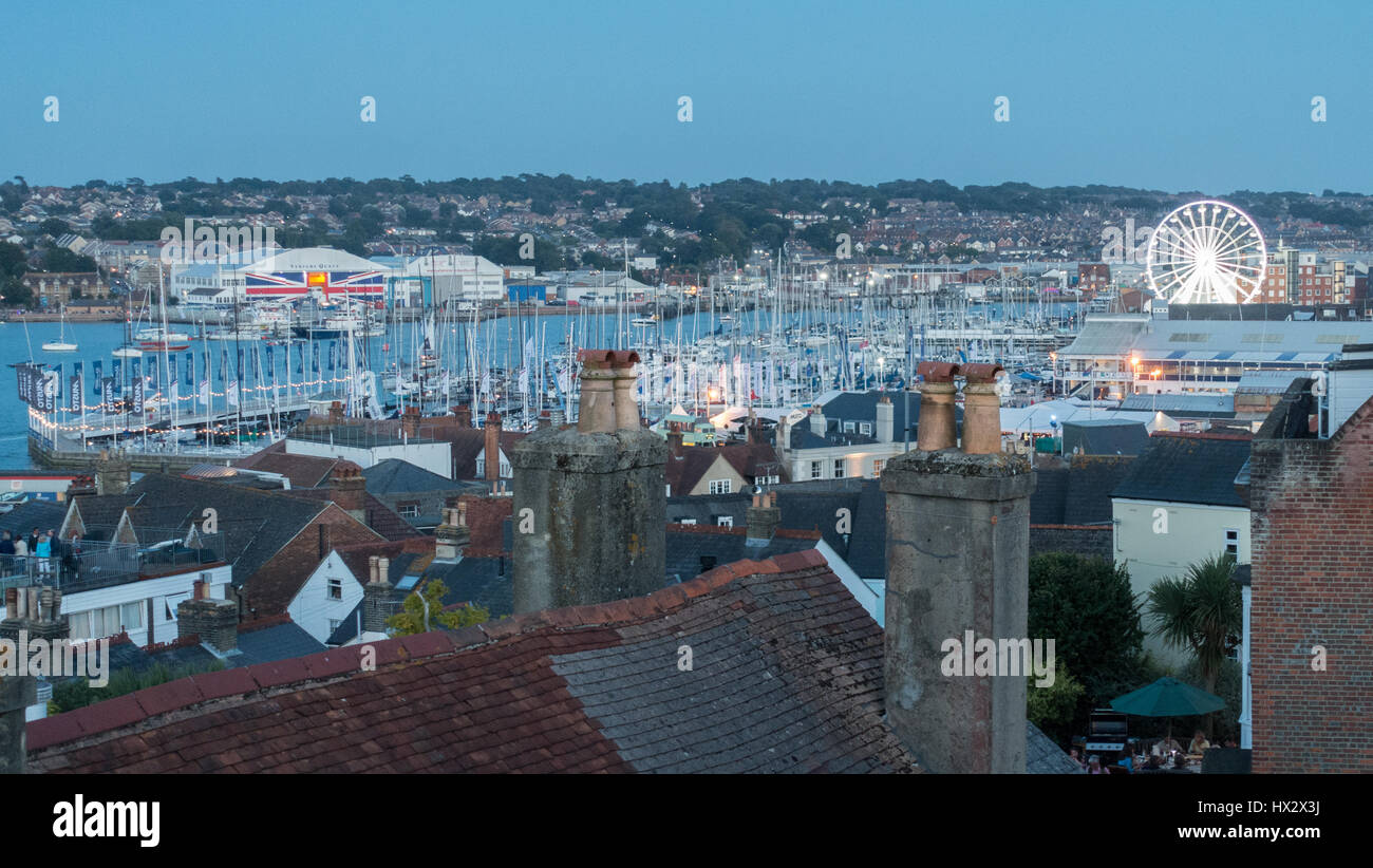 roofscape over east and west Cowes and Medina river during Cowes Week regatta yacht race in August ferris wheel in background at dusk, Cowes UK Stock Photo