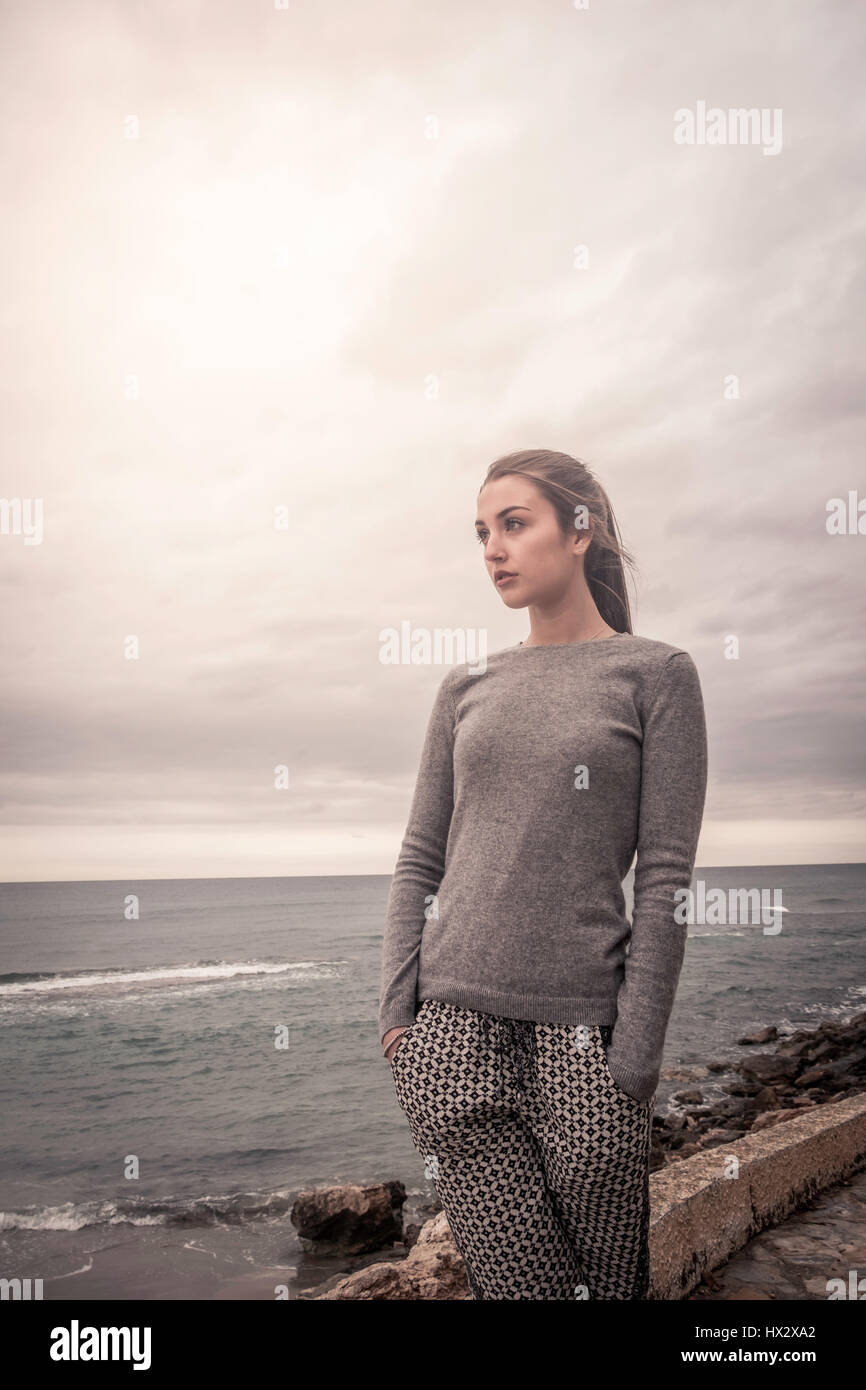 Teenage girl daydreaming while gazing at the ocean. Stock Photo