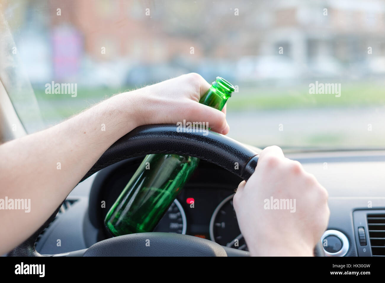Drunk man driving his car and drinking alcohol Stock Photo