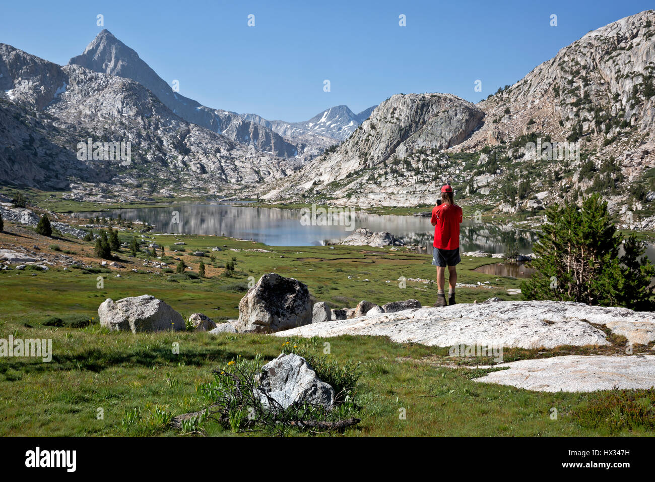 CA03117-00...CALIFORNIA - Hiker photographing Evolution Lake located along the JMT/PCT in Kings Canyon National Park. Stock Photo