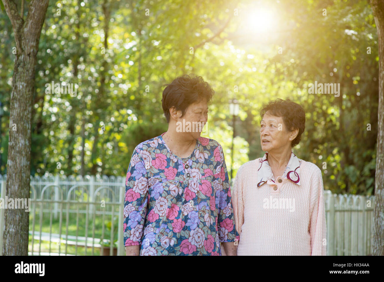 Candid shot of Asian senior adult women walking at outdoor garden park ...