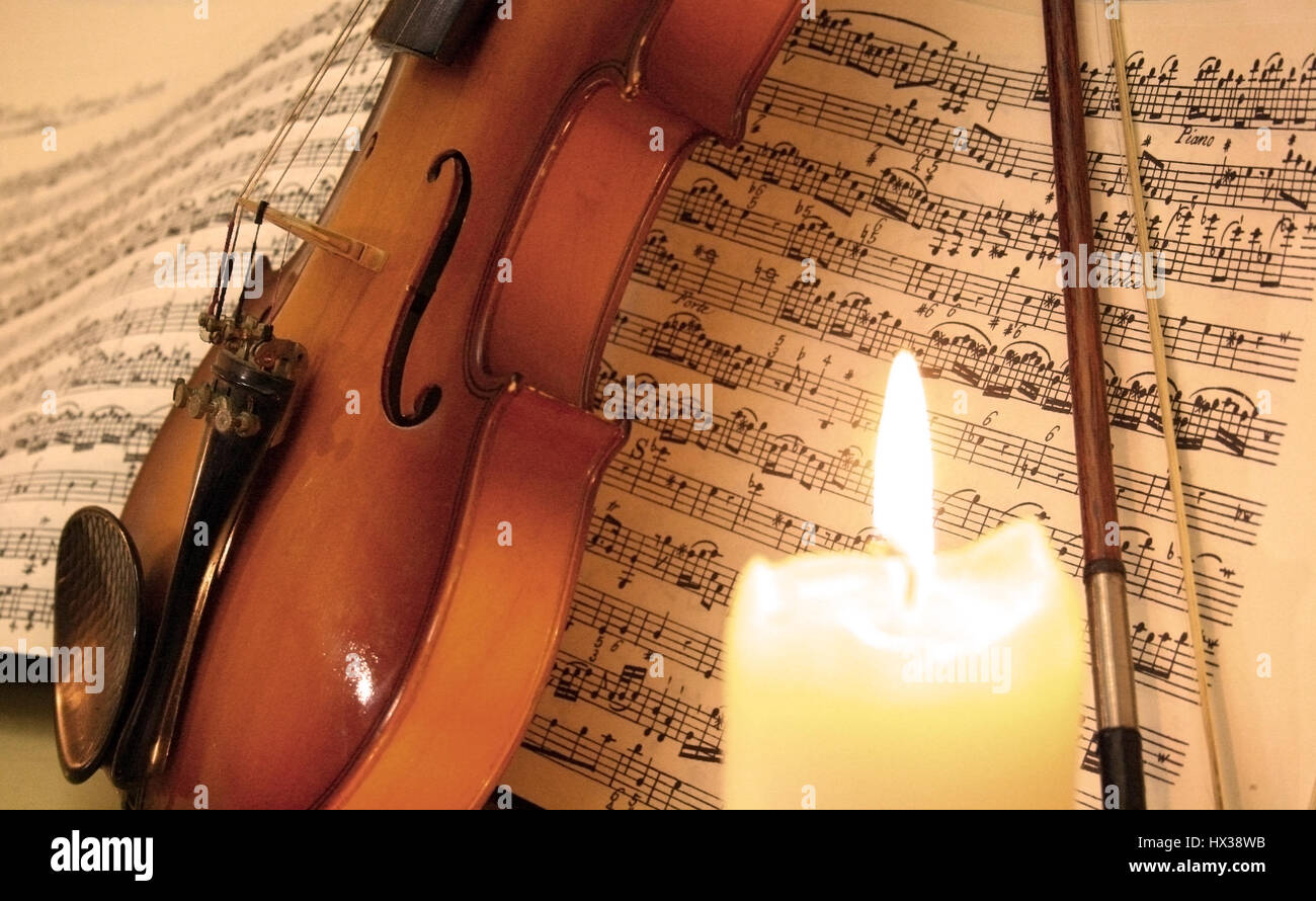 Violin and bow with music sheet and candle Stock Photo