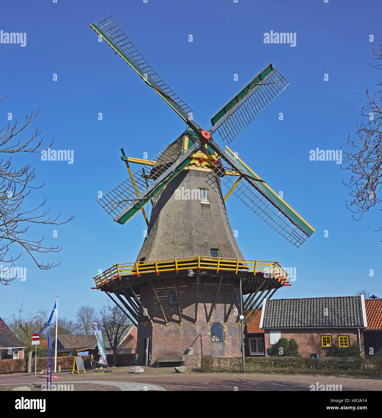 Grain mill 'De Hoop' or 'Molen van Buursink' in Markelo, the Netherlands, with green, red and yellow painted wooden parts, against a beautiful blue sk Stock Photo