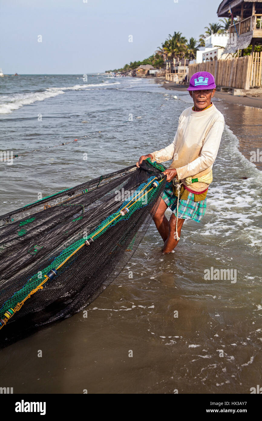 An old Filipino fisherman catches fish with a seine net at Baybay Beach in Roxas City, Panay Island, Philippines. Stock Photo
