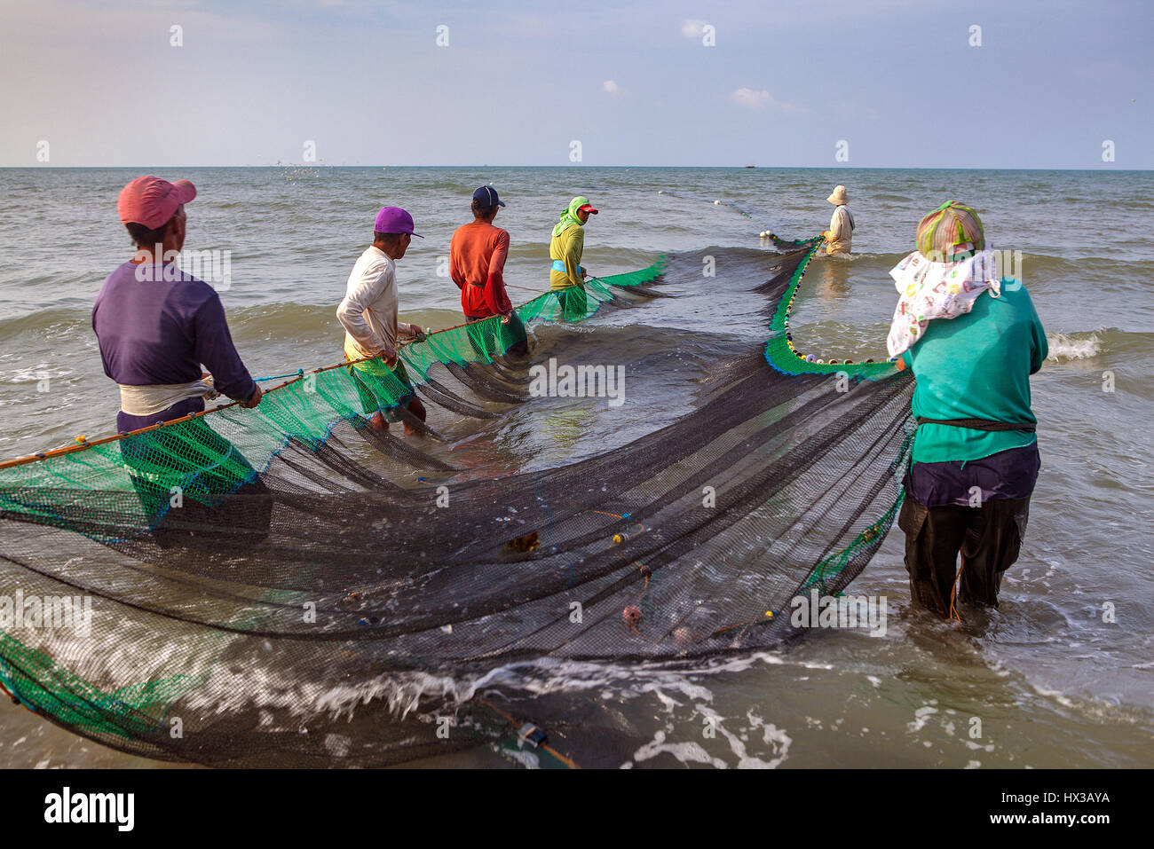A group of Filipino fishermen haul their seine fishing net to