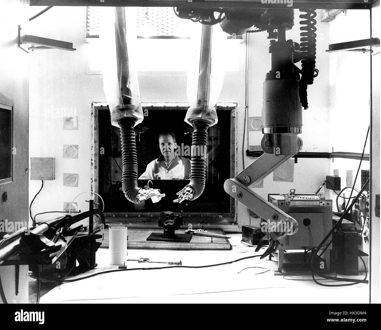 A rear view of the interior of one of the Metallurgy Hot Cells and a researcher operating it, 1970. Image courtesy US Department of Energy. Stock Photo