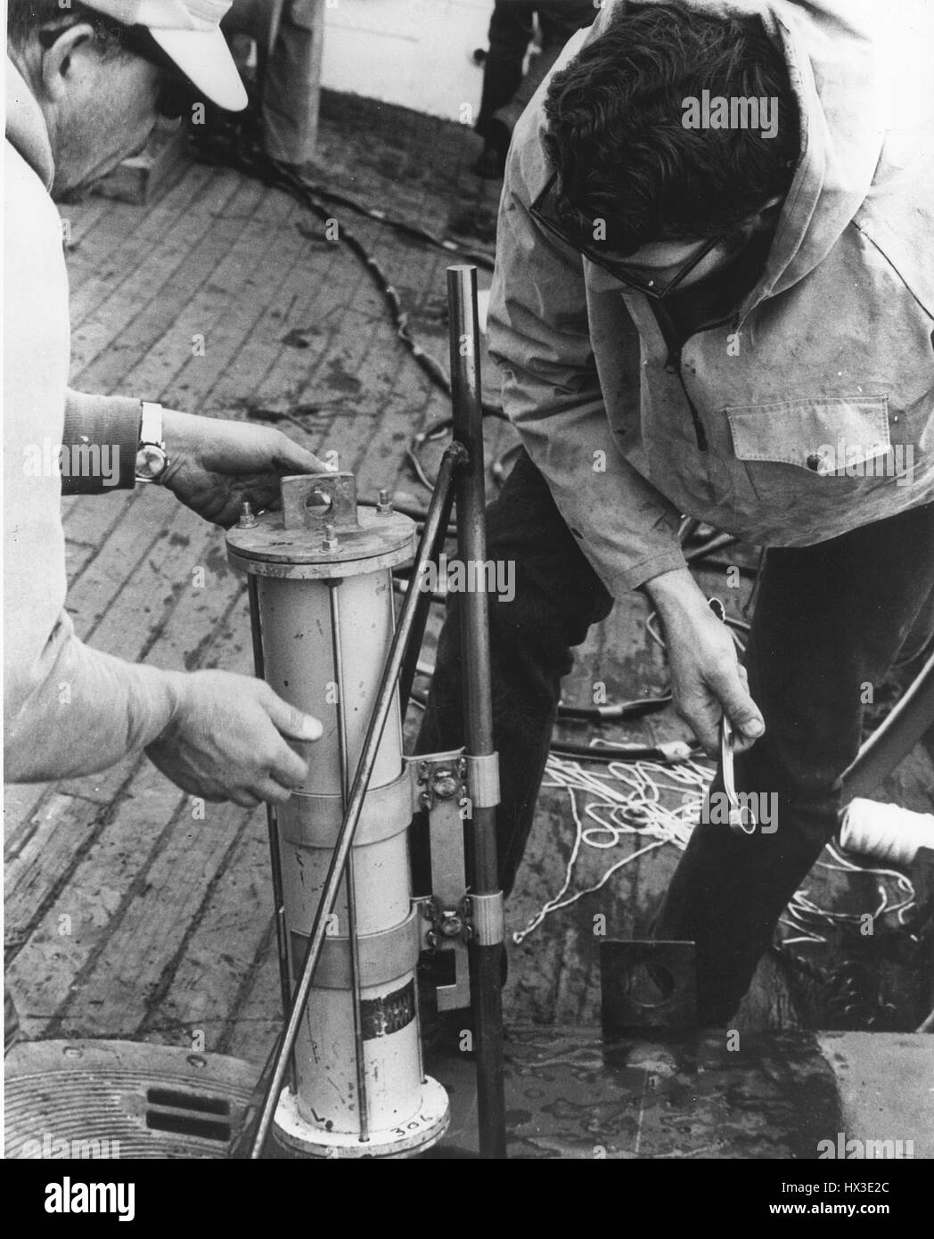 Researchers with the the U.S. Atomic Energy Commission's Argonne National Laboratory Radiologist Physics Division fasten an instrument that records temperature to an 800 pound steel anchor before submerging it in Lake Michigan, 1972. Image courtesy US Department of Energy. Stock Photo