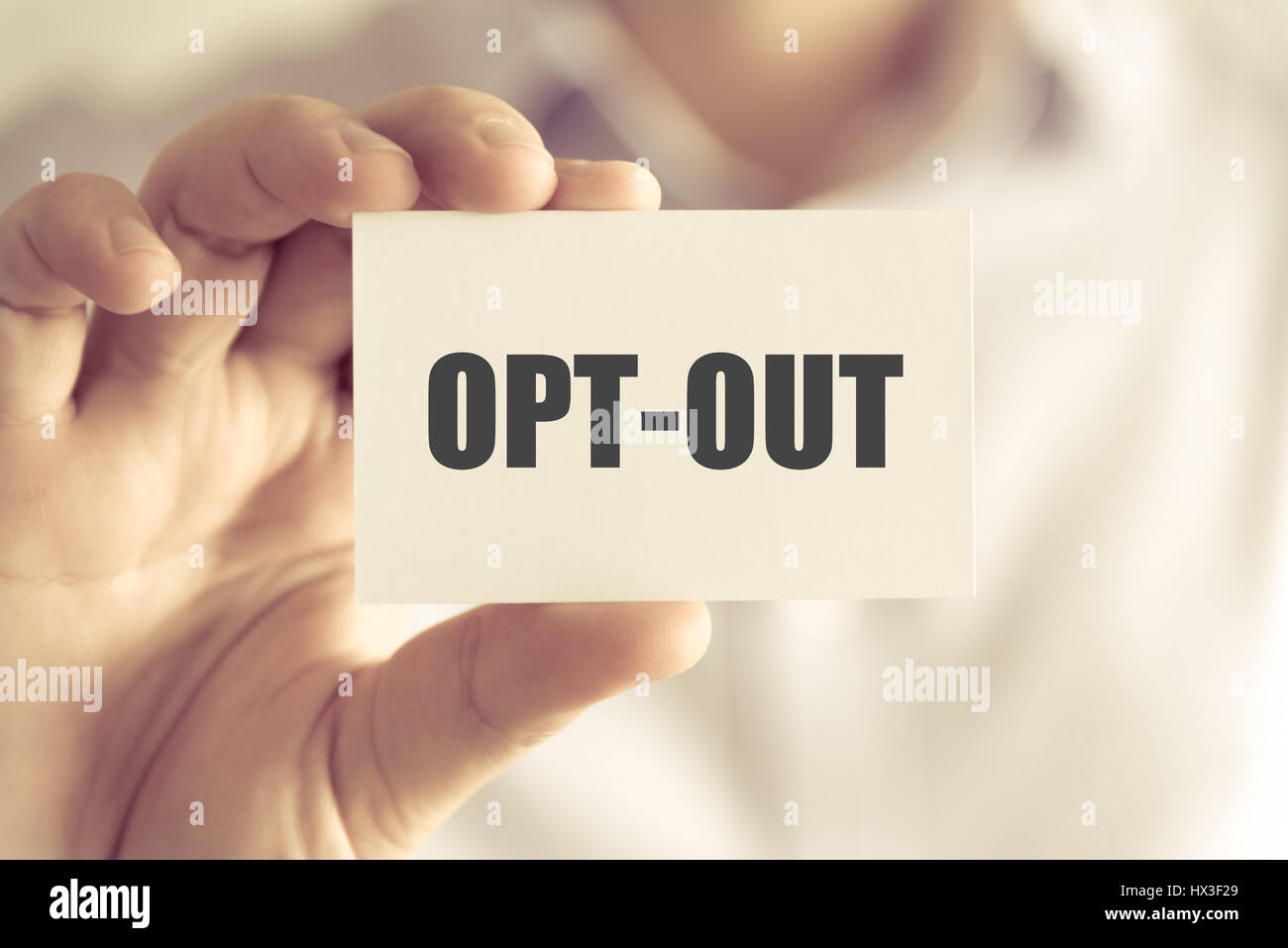 Closeup on businessman holding a card with text OPT-OUT, business concept image with soft focus background and vintage tone Stock Photo