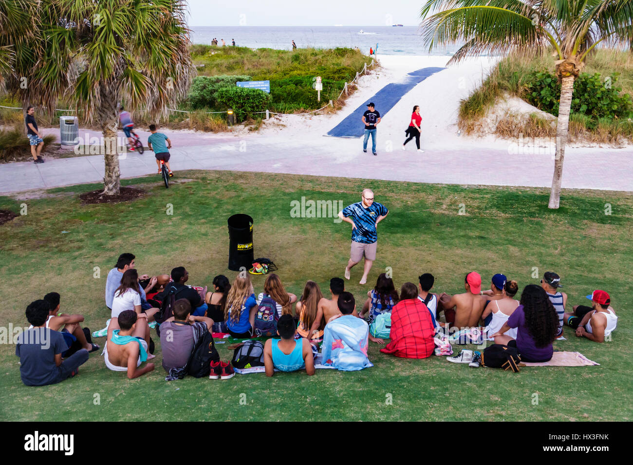 Miami Beach Florida,South Pointe Park,public park,adult adults man men male,woman women female lady,sitting seated on grass,lawn,young adults,bible st Stock Photo