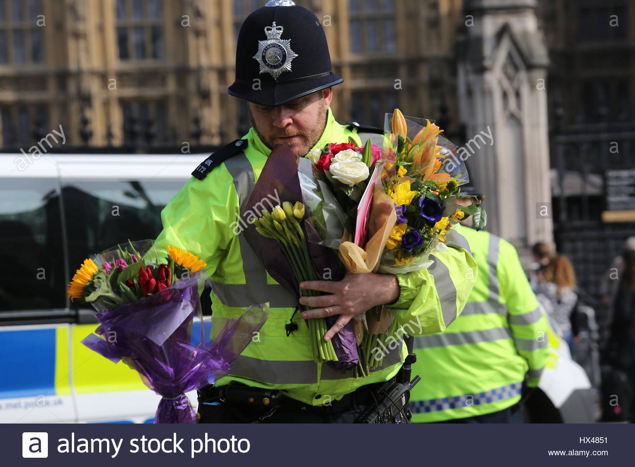 Westminster, London, UK. 24th March, 2017. A policeman carries flowers across the road at Westminster London this afternoon. Credit: reallifephotos/Alamy Live News Stock Photo