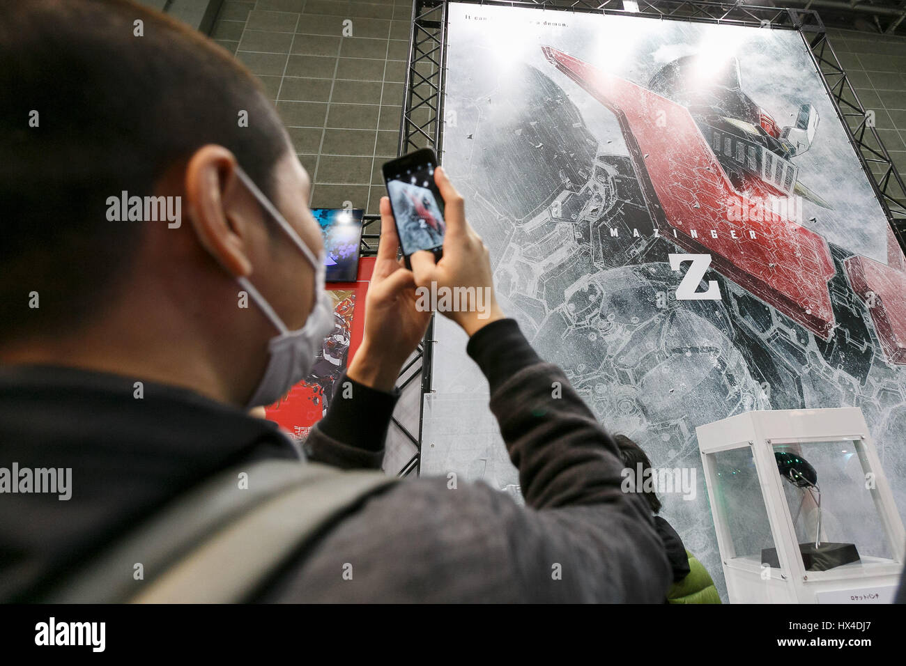 Tokyo, Japan. 25th March, 2017. A visitor takes pictures of a huge poster of Mazinger Z on display during the AnimeJapan 2017 at Tokyo Big Sight on March 25, 2017, Tokyo, Japan. AnimeJapan 2017 is a trade show promoting ''Everything Anime'' to local and foreign fans and businesses. The show is held over four-day days with March 23-24 reserved for business visitors and March 25-26 for the public. It is expected to attract some 120,000 visitors, including cosplayers. Credit: Rodrigo Reyes Marin/AFLO/Alamy Live News Stock Photo