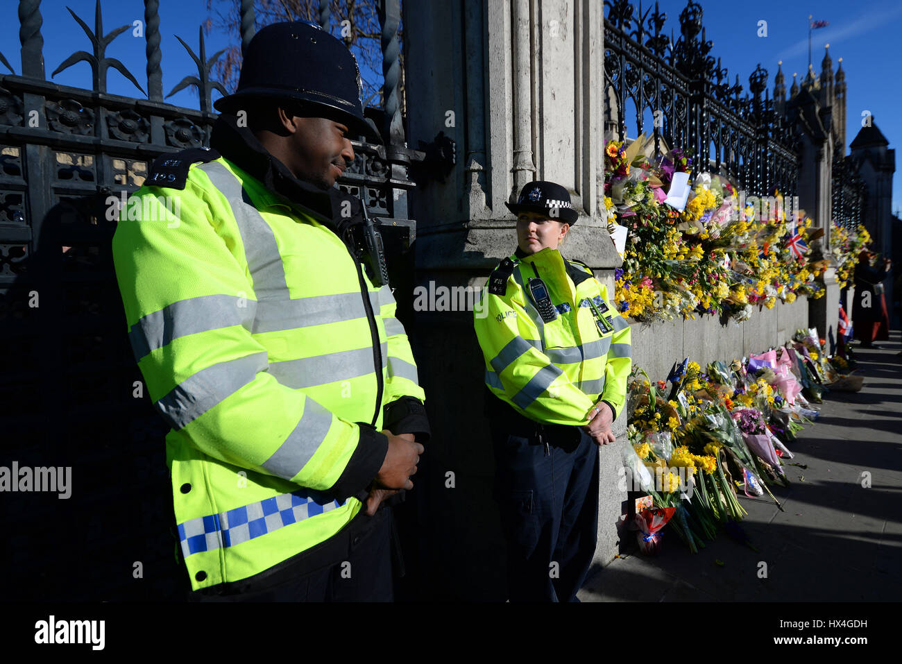 Flowers attached to the fence at the Palace of Westminster by marchers demonstrating against 'Brexit'. They were placed to honour the lives lost during the terrorist attack. Black policeman Stock Photo