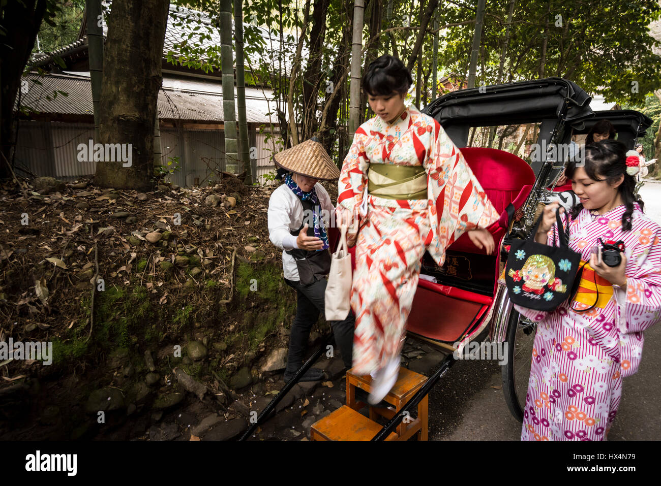 A rickshaw pulled by a male in traditional worker's uniform and two female passengers in Kimono, Japanese traditional costume, Kyoto, Japan Stock Photo