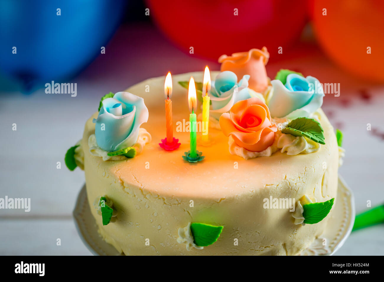 Birthday cake with lighted candles and marzipan roses Stock Photo - Alamy