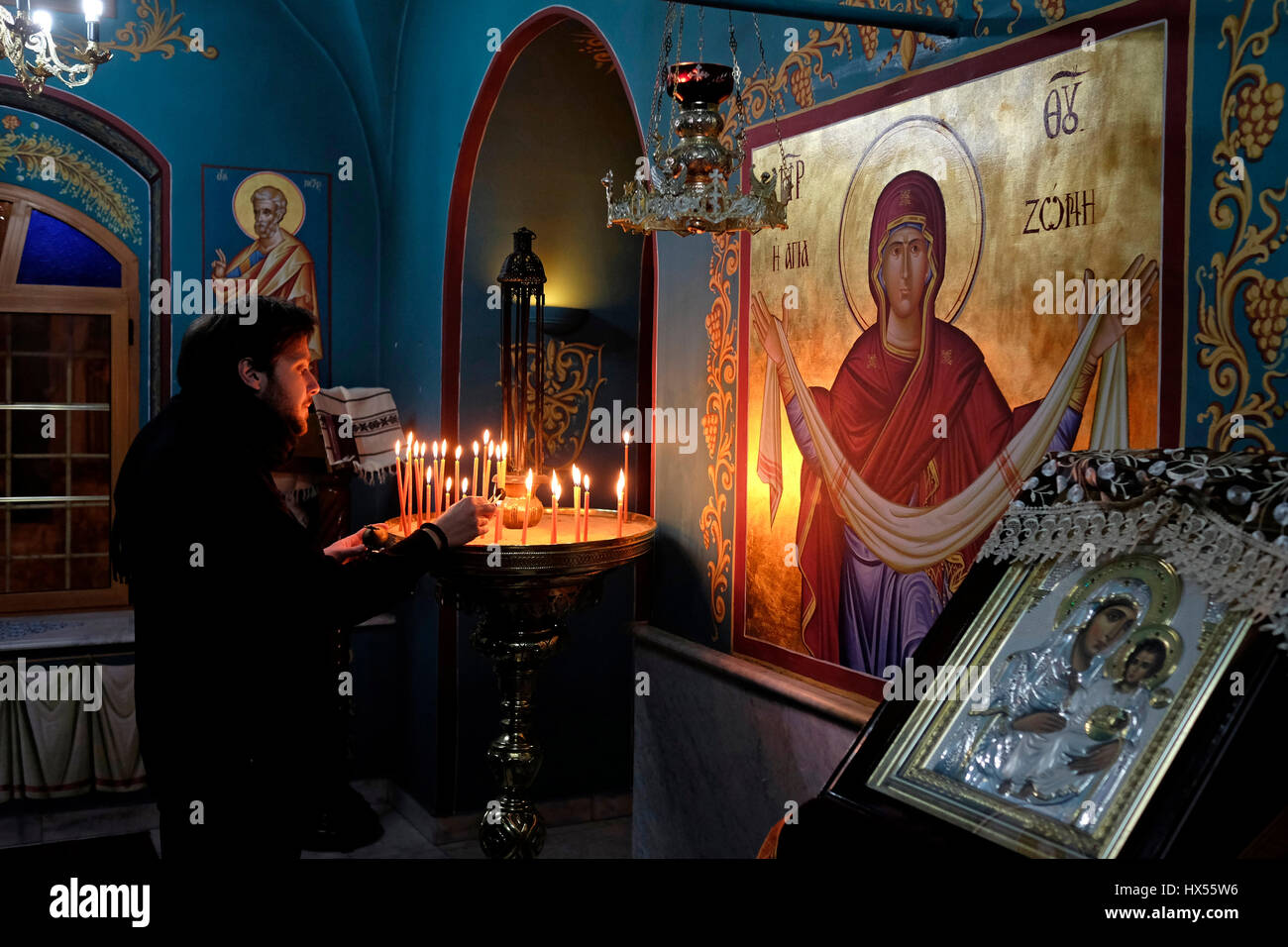 A Christian Orthodox worshiper lighting candles inside the church of