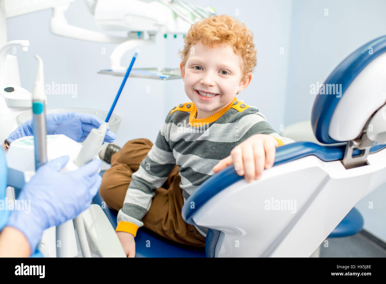 Portrait of a happy young boy with a toothy smile sitting on the dental ...