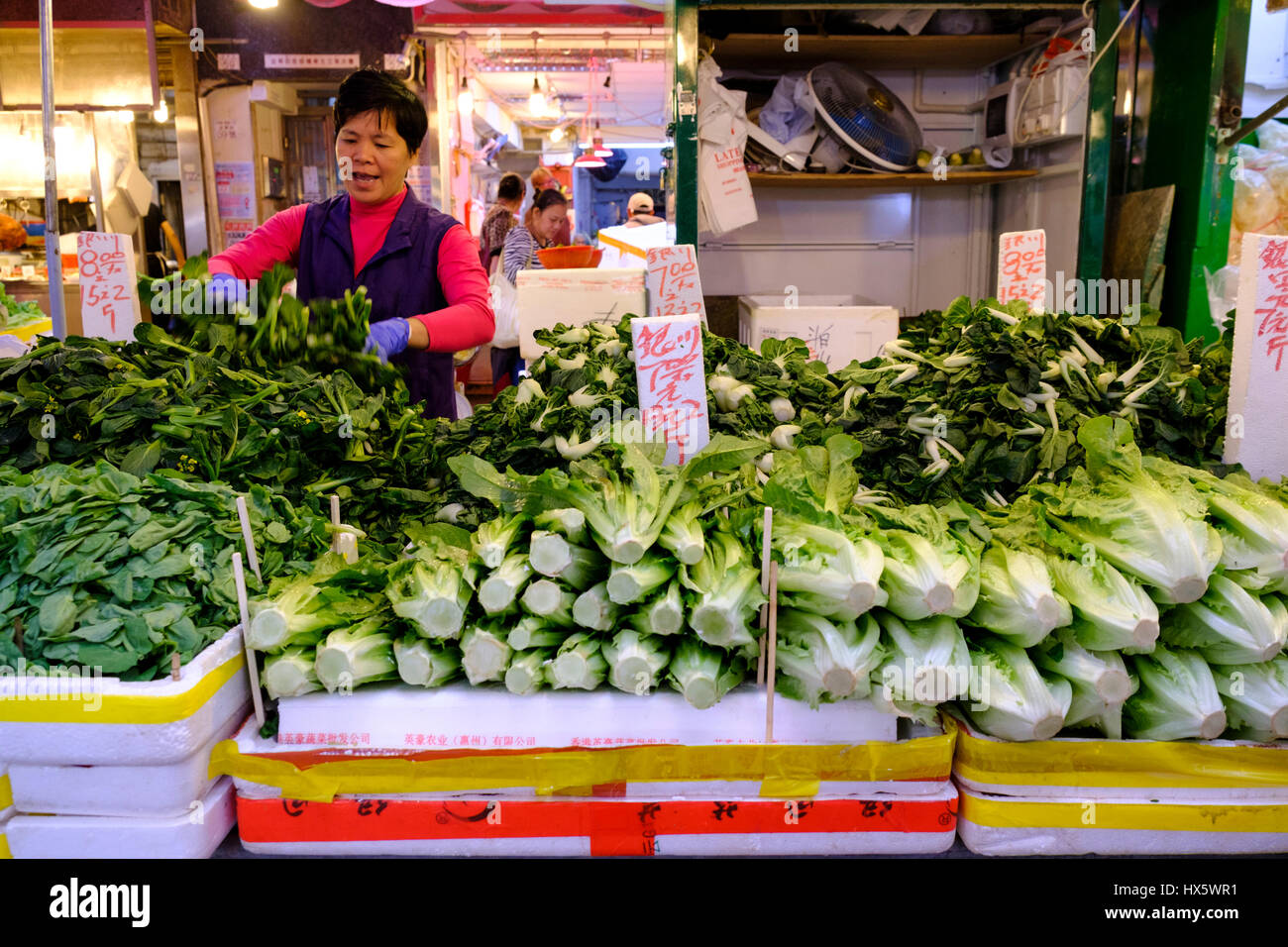 A woman selling vegetables at her street stall in Shau Kei Wan market. Hong Kong Island, Hong