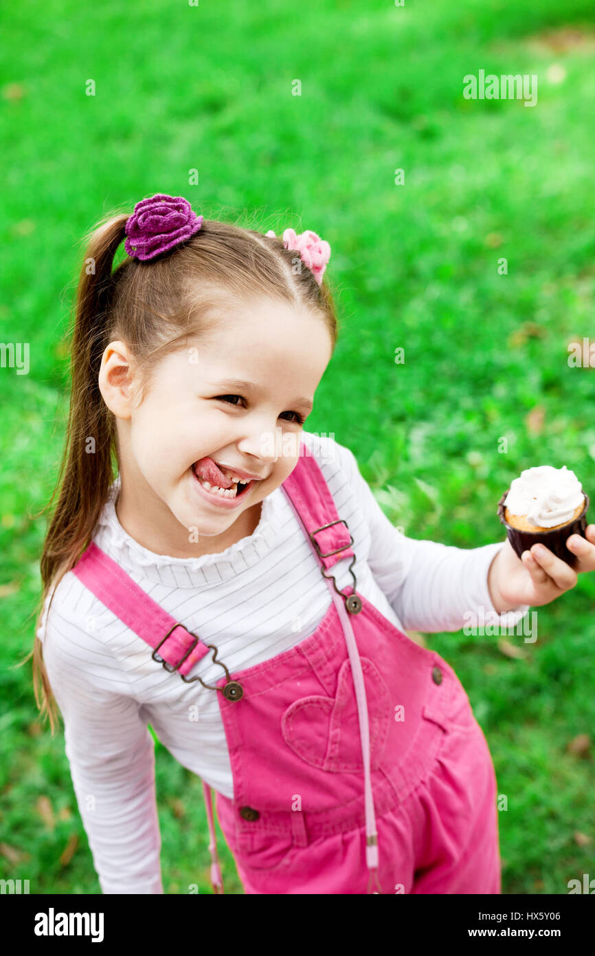 Happy little girl eating cake and having fun at the park. Child outdoor. Stock Photo