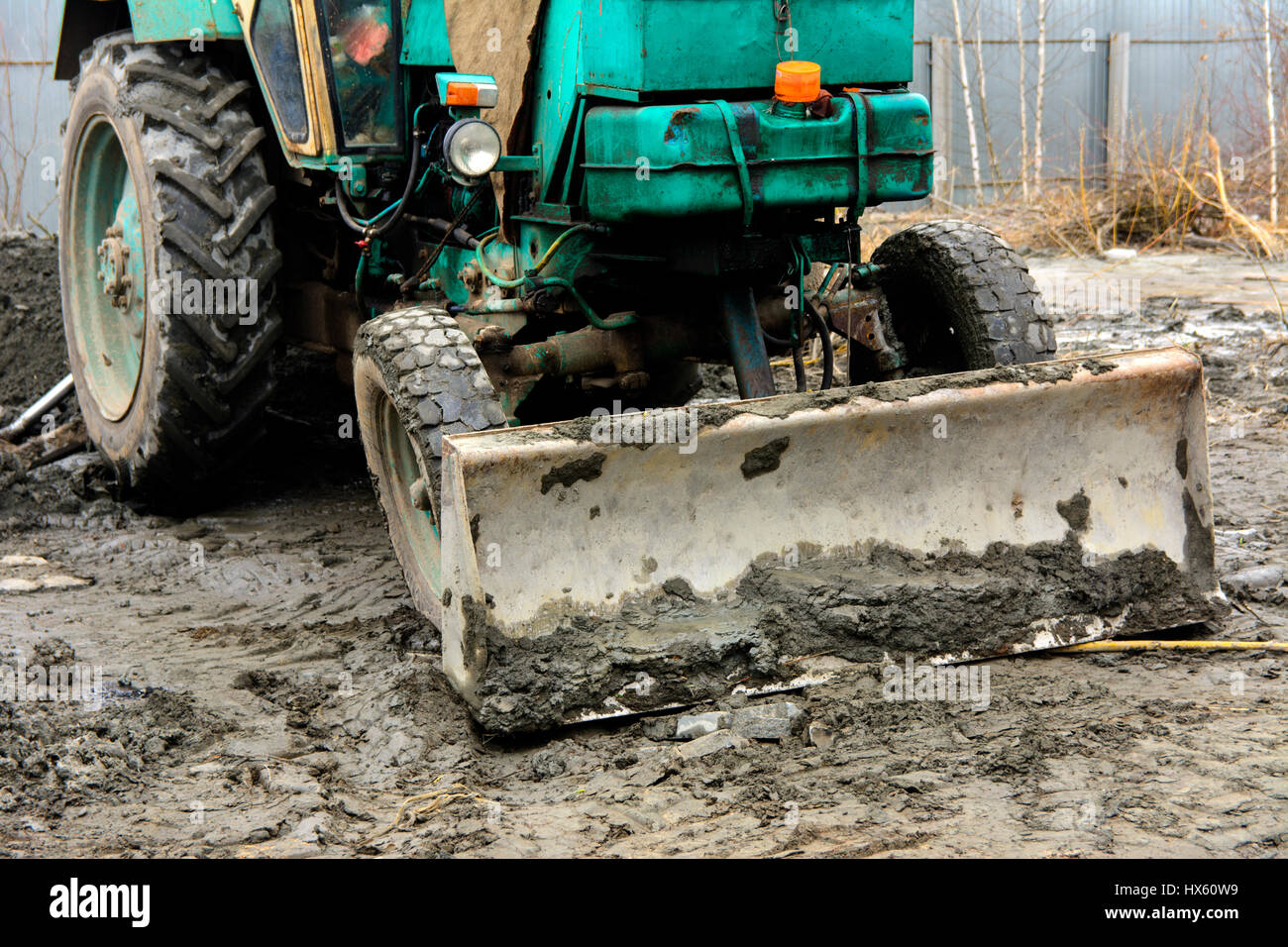 An old Soviet tractor digs and loads waste stone processing near the shop Stock Photo