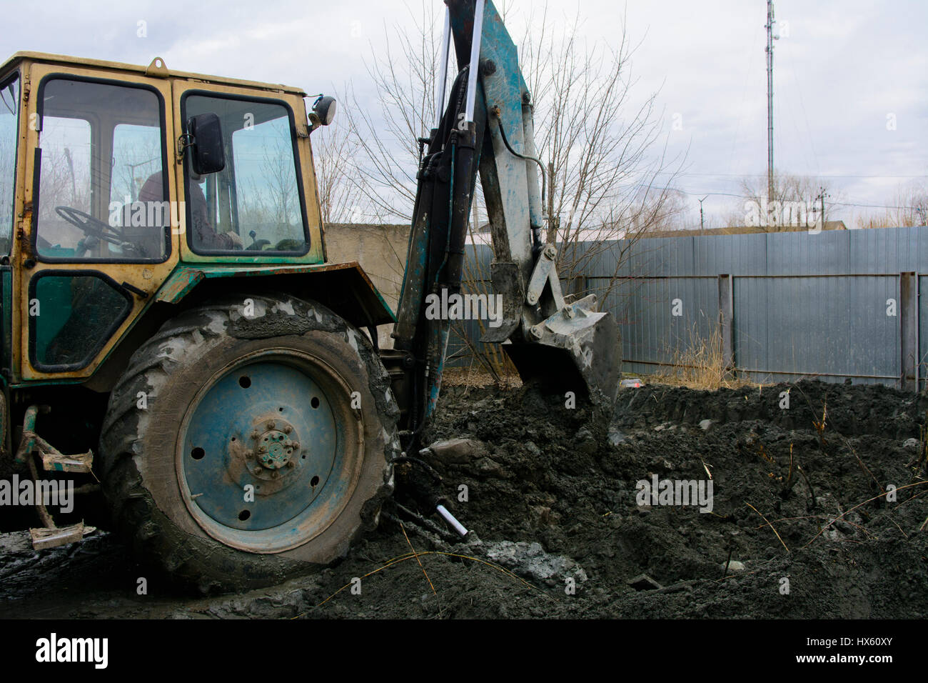 An old Soviet tractor digs and loads waste stone processing near the shop Stock Photo