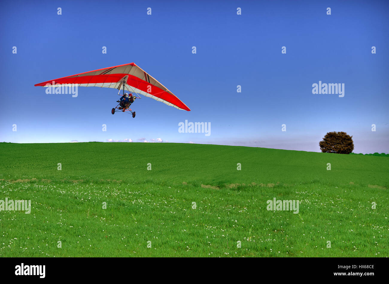 A hang glider flying over a country scene, in a very clear, sunny day Stock Photo