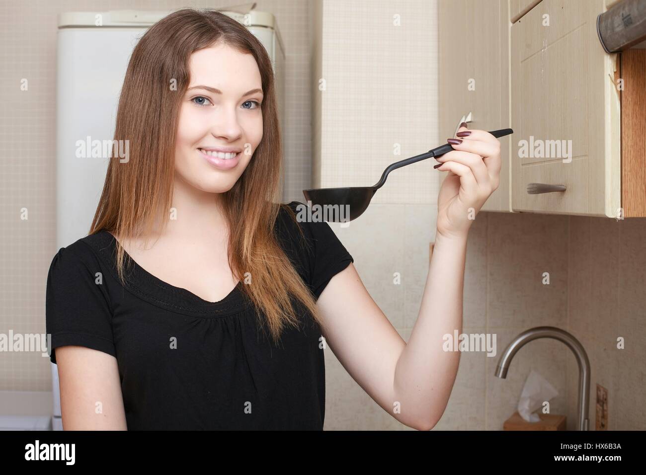 Housewife throwing out garbage in the kitchen opening a cupboard door Stock Photo