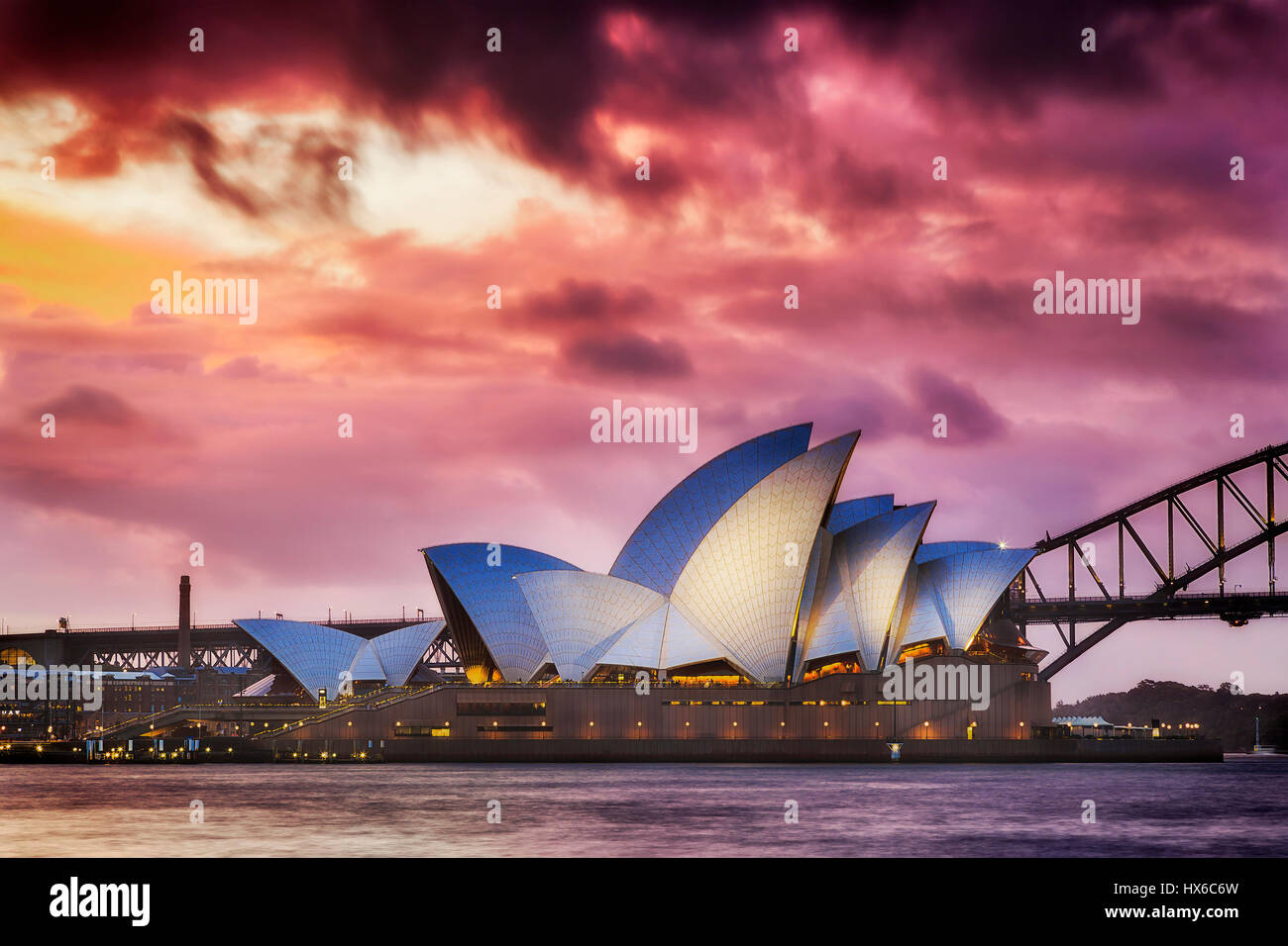 Sydney, Australia - 19 March 2017: Magical sunset over world famous landmark - Sydney Opera house and Harbour Bridge. Side view of illuminated opera. Stock Photo