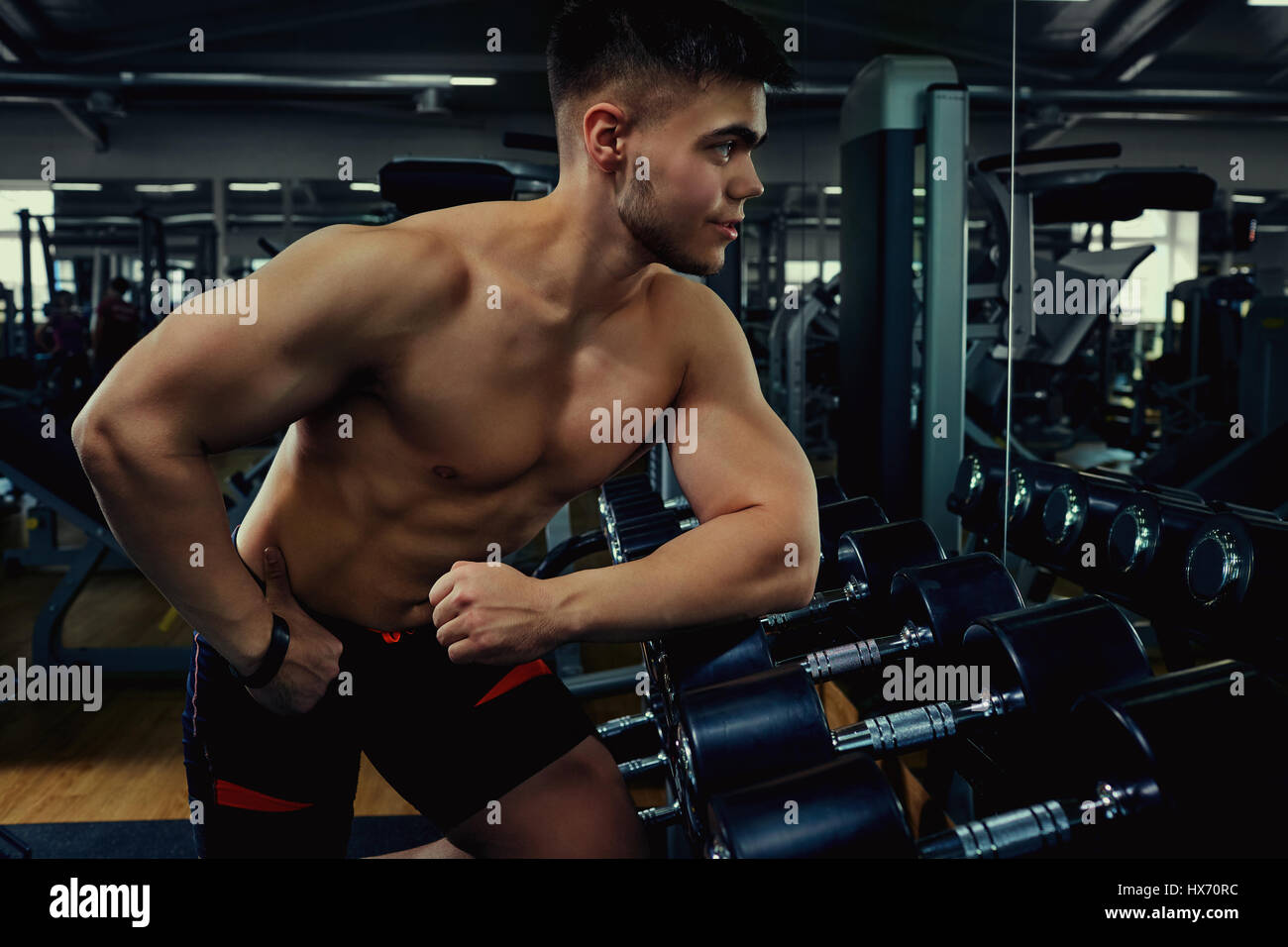 Sportsman bodybuilder athlete  with dumbbells in the gym Stock Photo