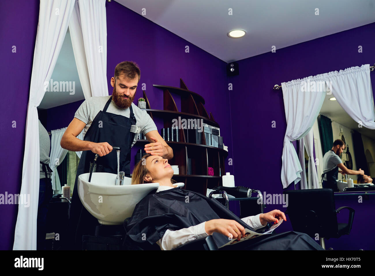 A hairdresser  man washes hair head to the client in the chair b Stock Photo