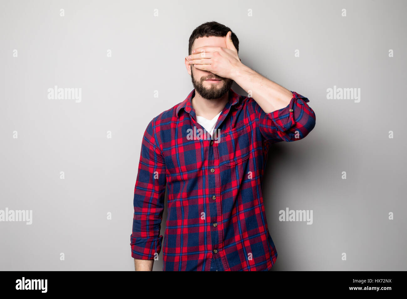 Portrait of a young casual man covering eyes with hand isolated on the ...