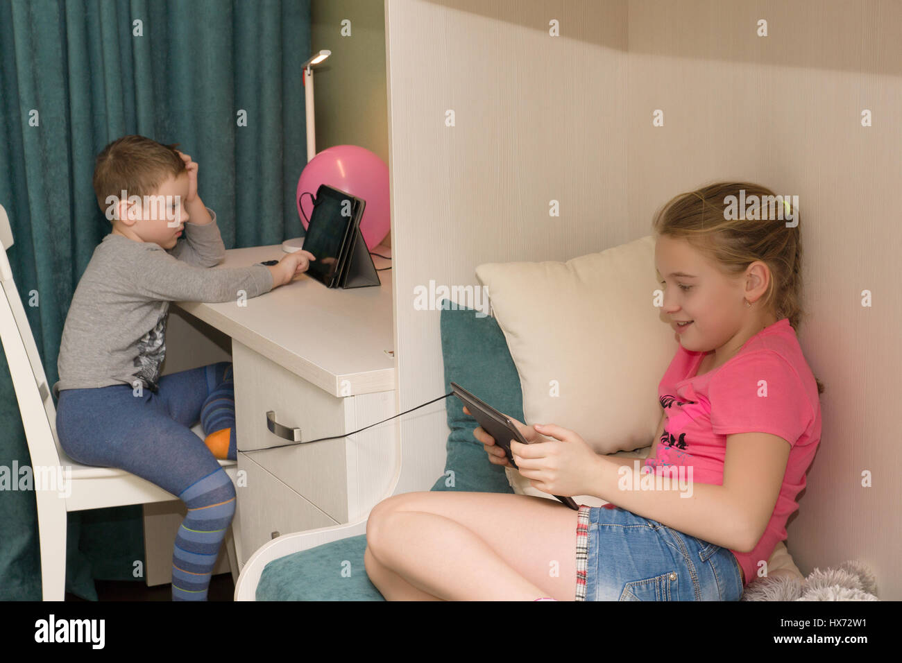 boy and girl sit in my room and play on tablets Stock Photo