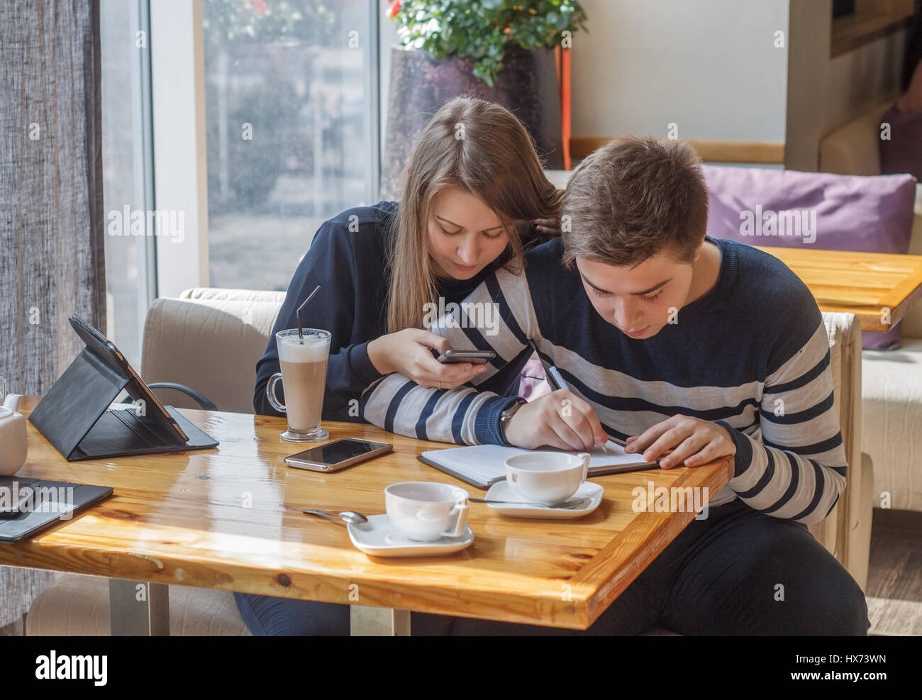 Beautiful young couple  sitting in cozy coffee shop. Couple in love making planning of life and writing in notepad. Stock Photo