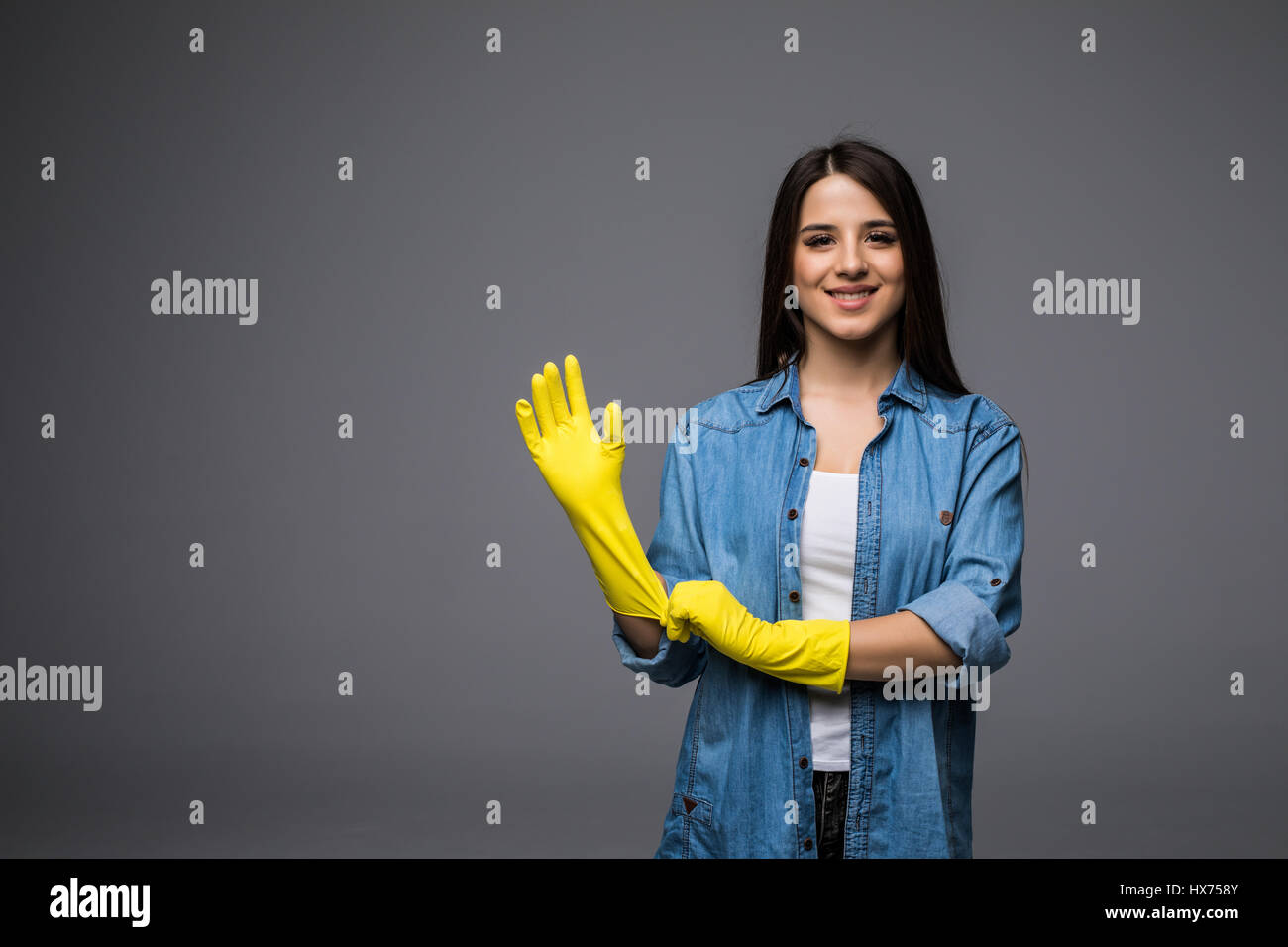 Cleaning lady getting spring cleaning ready putting on rubber gloves. Cleaning woman smiling happy at camera Stock Photo