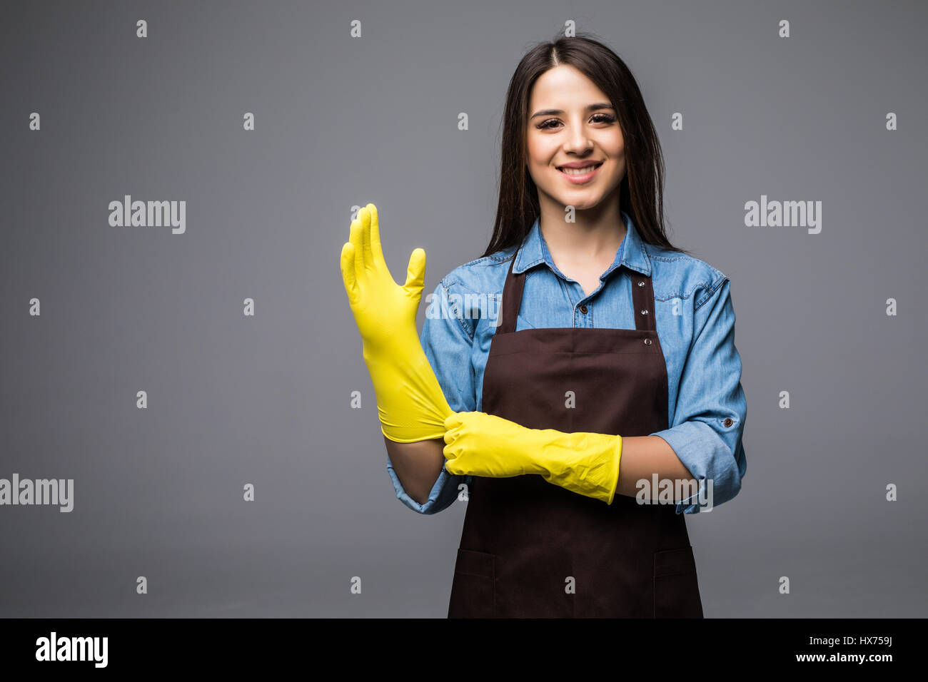 Cleaning lady getting spring cleaning ready putting on rubber gloves. Cleaning woman smiling happy at camera Stock Photo