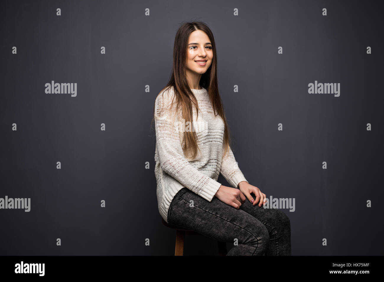 Portrait of pretty young woman with long hair in white shirt sitting on ...