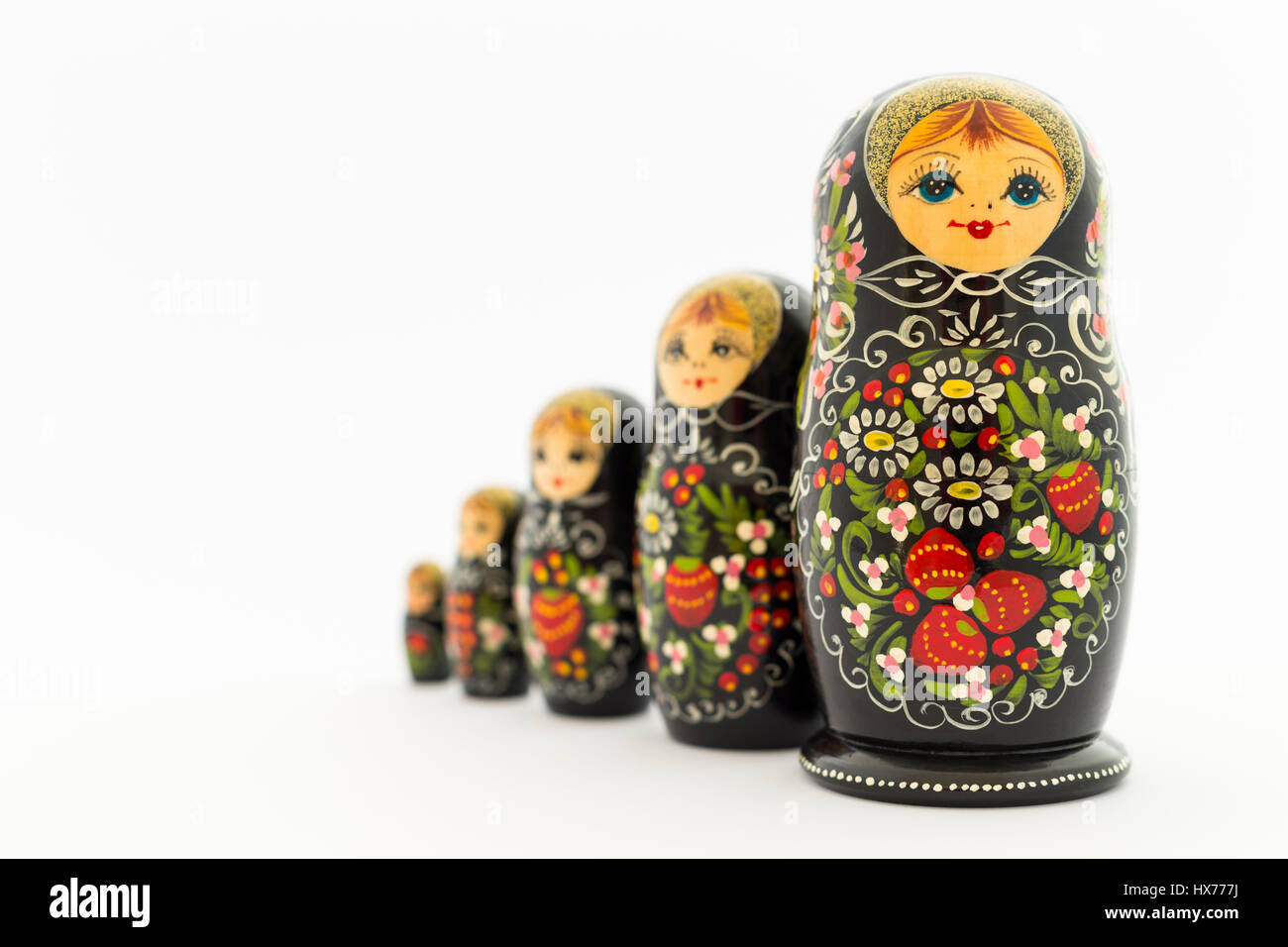 Beautiful black russian nesting dolls (matryoshka dolls) with white, green and red painting in front of white background Stock Photo