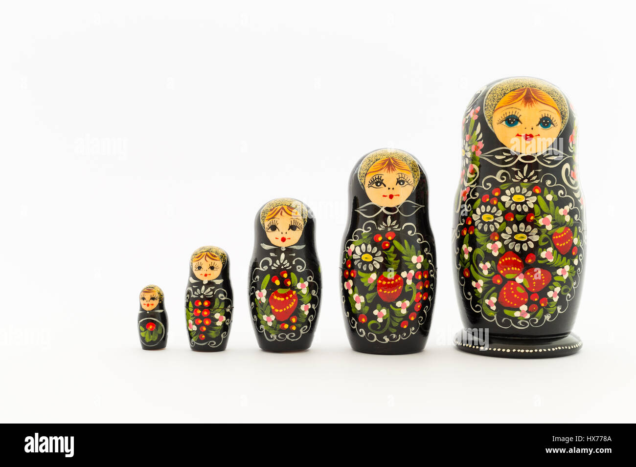 Beautiful black russian nesting dolls (matryoshka dolls) with white, green and red painting in front of white background Stock Photo