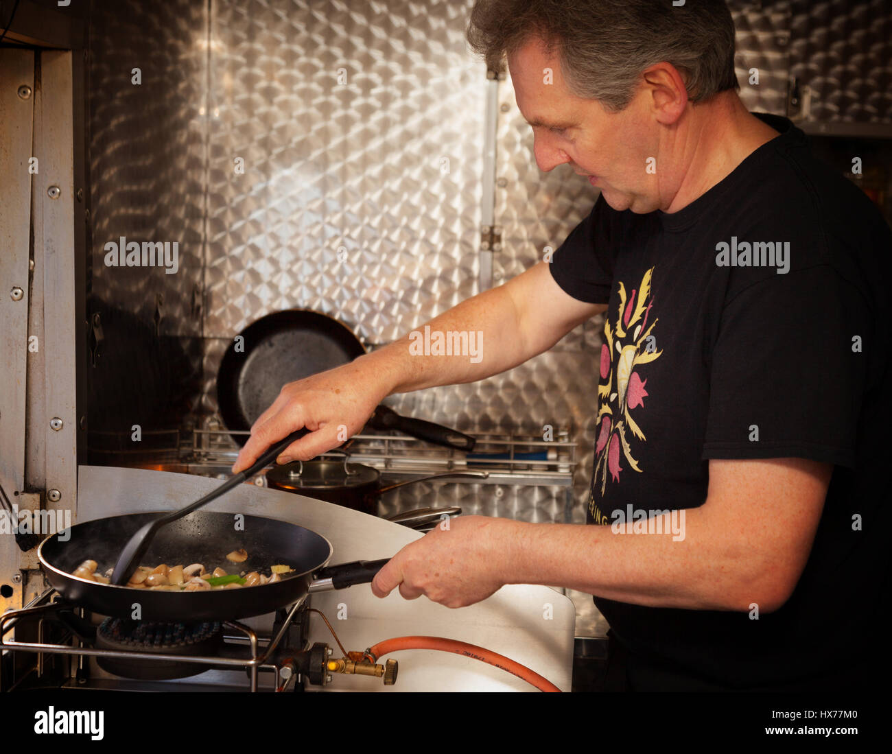 Man cooking food - vegetables in a  frying pan on a calor gas stove, England UK Stock Photo